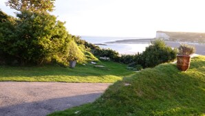 Un sentier qui mène à une zone herbeuse offrant une vue sur la mer et les falaises.