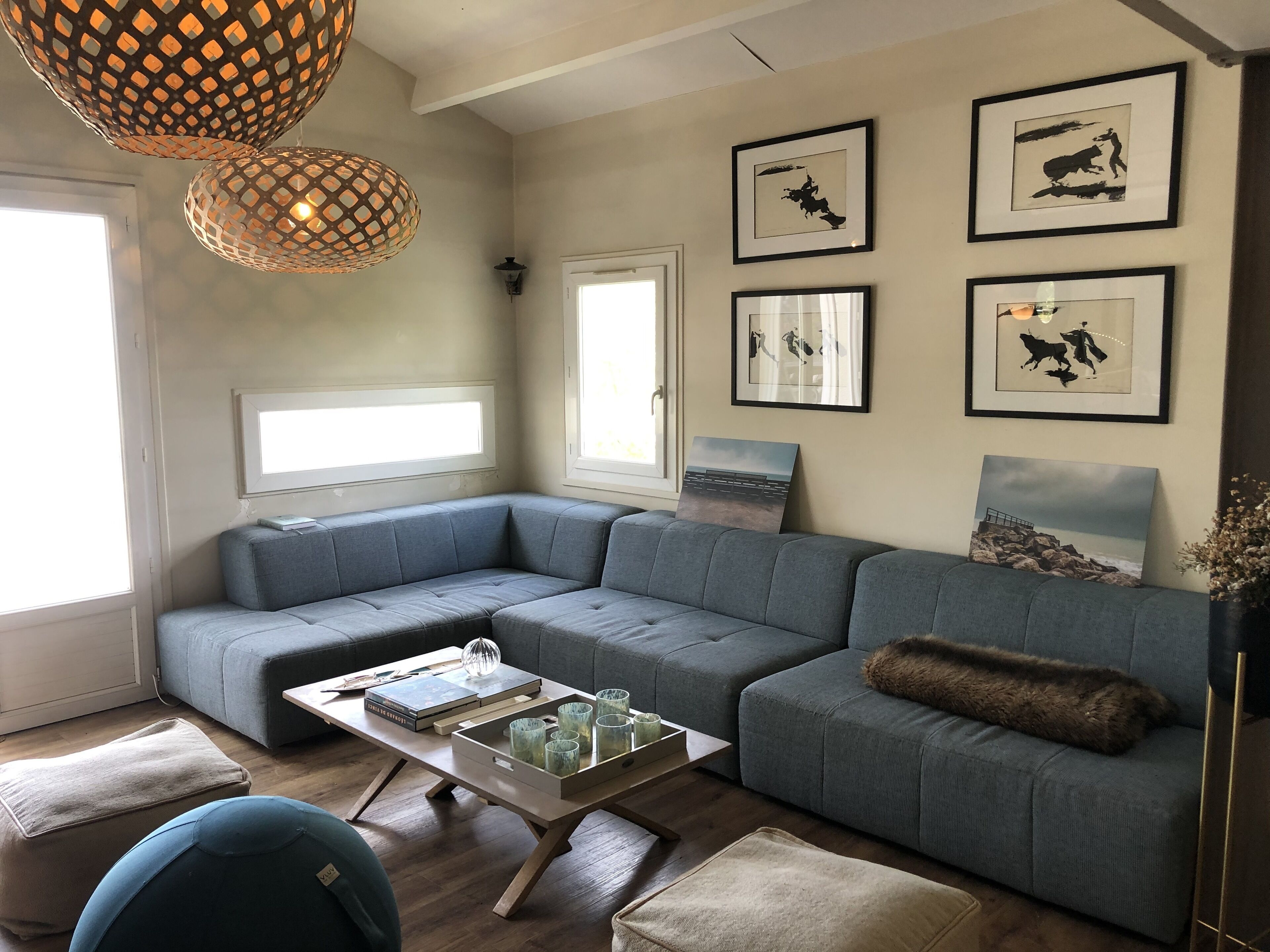 Un salon moderne avec un canapé d’angle, une table basse et des œuvres d’art accrochées au mur.