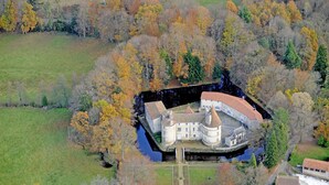 Vista aérea de un castillo rodeado por un foso, con un río que lo acompaña.