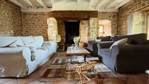 Una sala de estar acogedora con paredes de piedra, una chimenea y dos sofás.