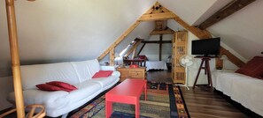 A loft-style room with a white sofa, red accents, a wooden table, and a TV.