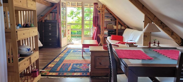 A cozy attic bedroom with a bed, a desk, a chair, and a bookshelf.