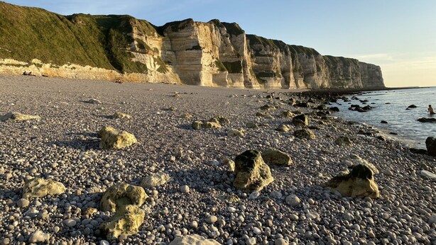 Une plage rocheuse avec de hautes falaises en arrière-plan.