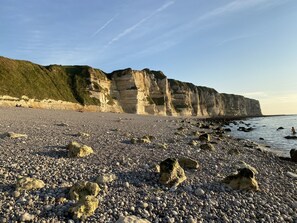 A rocky beach with large cliffs in the background.