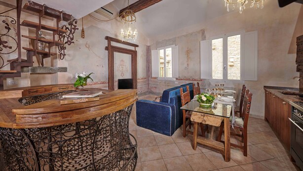 Una cocina rústica con una isla de madera, una mesa de comedor con sillas y un sofá azul.