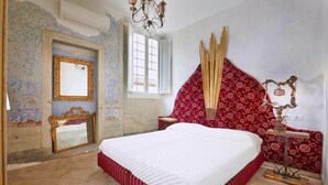 Un dormitorio con una cama grande, un espejo, una araña y una pared con diseño.