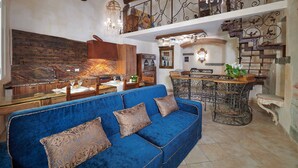 Un amplio espacio habitable con un sofá azul, armarios de madera y una araña.