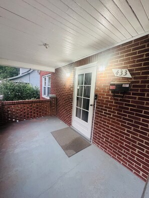 A brick exterior with a white door, a mailbox, and a number sign indicating the address.