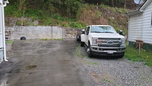 Un camion blanc est garé dans une allée menant à une maison, et un chemin de gravier part de cette allée.