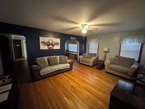 A living room with a dark wall, a ceiling fan, and two couches.