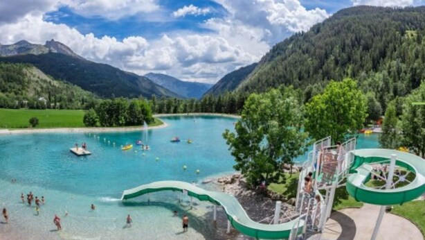 A resort with a swimming pool, water slides, and a mountainous backdrop. - Studio (Allos)