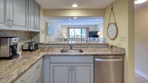 Una cocina con encimeras de granito, electrodomésticos de acero inoxidable y lavavajillas.