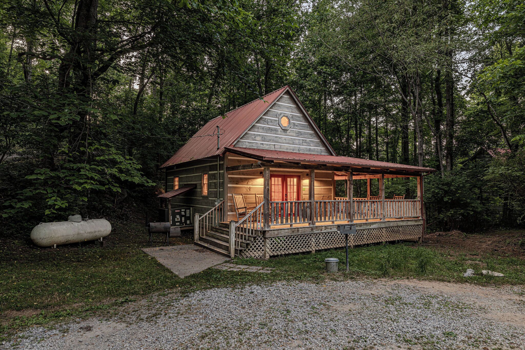 A cabin with a porch, wooden deck, and a small front yard.