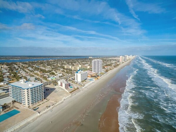 A coastal cityscape with a beach, high-rise buildings, and a clear sky.