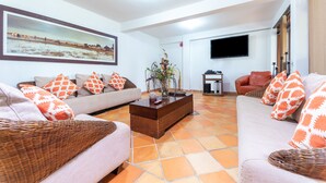 A living room with two sofas, a coffee table, a TV, and a painting on the wall. - Hotel Casa Baquero (Villavicencio)