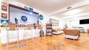 A hotel reception area with a reception desk, bar stools, a sofa, and a television. - Hotel Casa Baquero (Villavicencio)