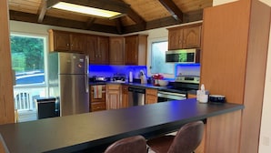 Una cocina moderna con armarios de madera, un refrigerador de acero inoxidable, un microondas y una isla grande con dos taburetes de bar.