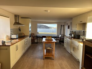 Eine moderne Küche mit Meerblick, Holzboden und einem Essbereich mit Tisch und Stühlen.
