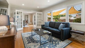 A modern living room with a dark blue sofa, a patterned rug, and a coffee table. - Southern Hills Stunner! 3bd/2bth (Tulsa)