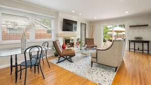 A spacious living room with a fireplace, comfortable seating, and a large TV mounted on the wall. - Southern Hills Stunner! 3bd/2bth (Tulsa)