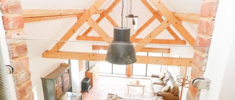 A loft-style room with exposed wooden beams, a dining area, and a cozy seating area.