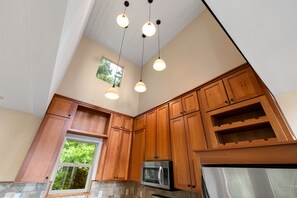 A kitchen with wooden cabinets, a microwave, and a stainless steel refrigerator.