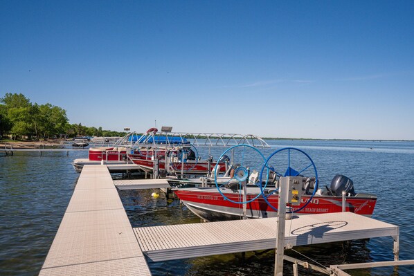 Guests can enjoy a serene lakeside setting with moored boats and a wooden pier.