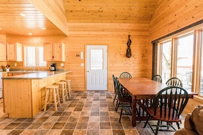Cozy cabin-style room with a kitchen area, dining space, and large window offering a view of the outdoors.