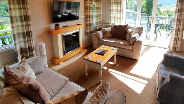Ein gemütliches Wohnzimmer mit Kamin, einer Couch, einem Couchtisch und einem Fernseher, der über dem Kamin angebracht ist.