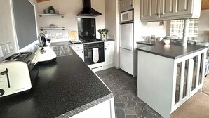 Eine moderne Küche mit schwarzem Arbeitsplatz, weißen Schränken, einem Herd, Backofen und einer eingebauten Mikrowelle.