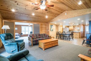 Relax in this spacious living area with a high ceiling, featuring a sofa set, coffee table, and dining table.