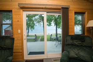 Enjoy a room with a sliding door leading to a deck with a table and chairs, offering a view of the beach and ocean.