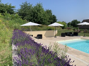 Ein Poolbereich mit Sitzgelegenheiten im Freien und einem Garten mit Lavendel.