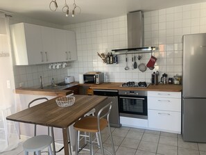 Cocina moderna con gabinetes blancos, encimera de madera, estufa a gas, microondas y refrigerador de acero inoxidable.