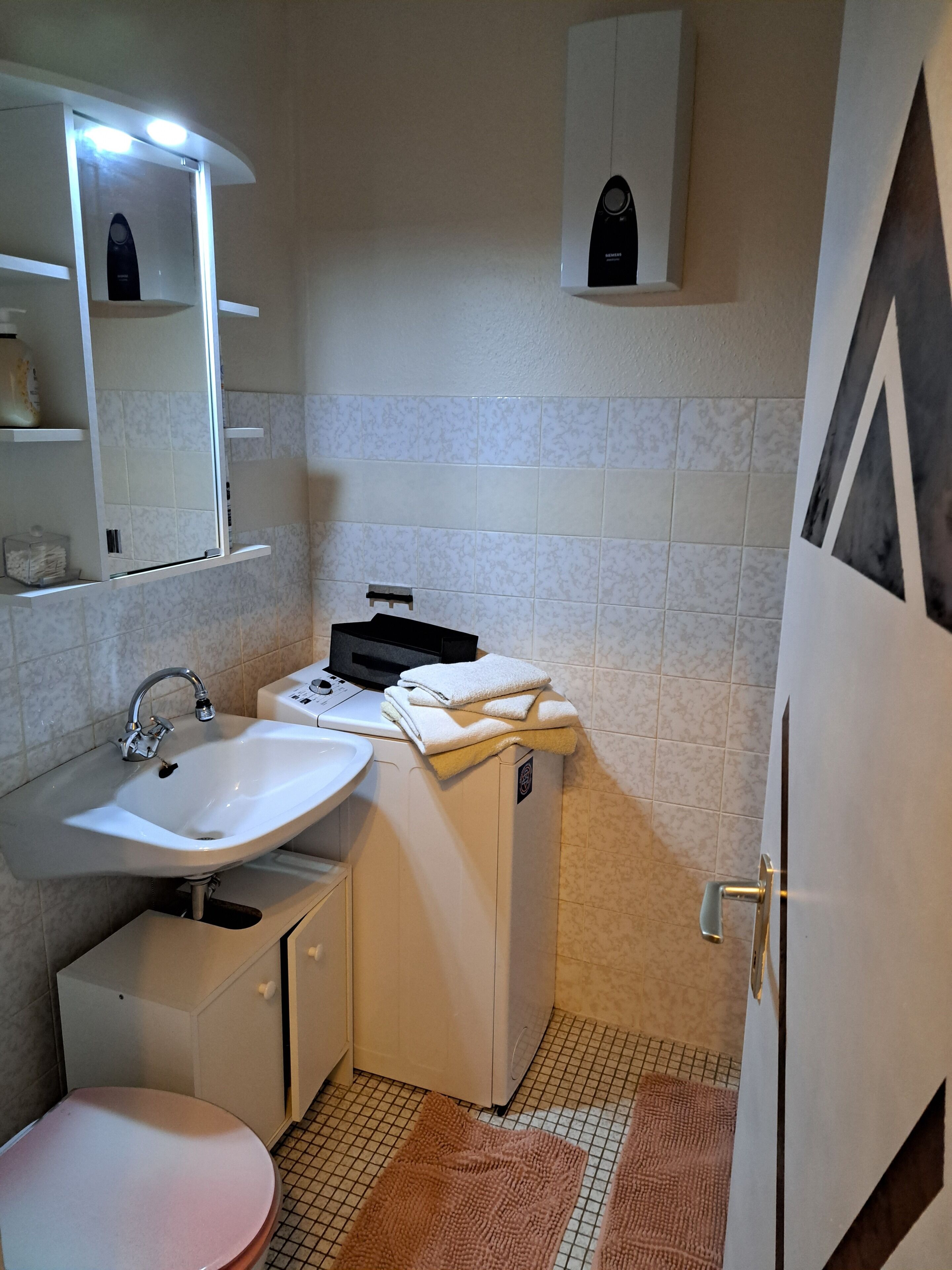 Un baño pequeño con lavabo, espejo y un mueble auxiliar.