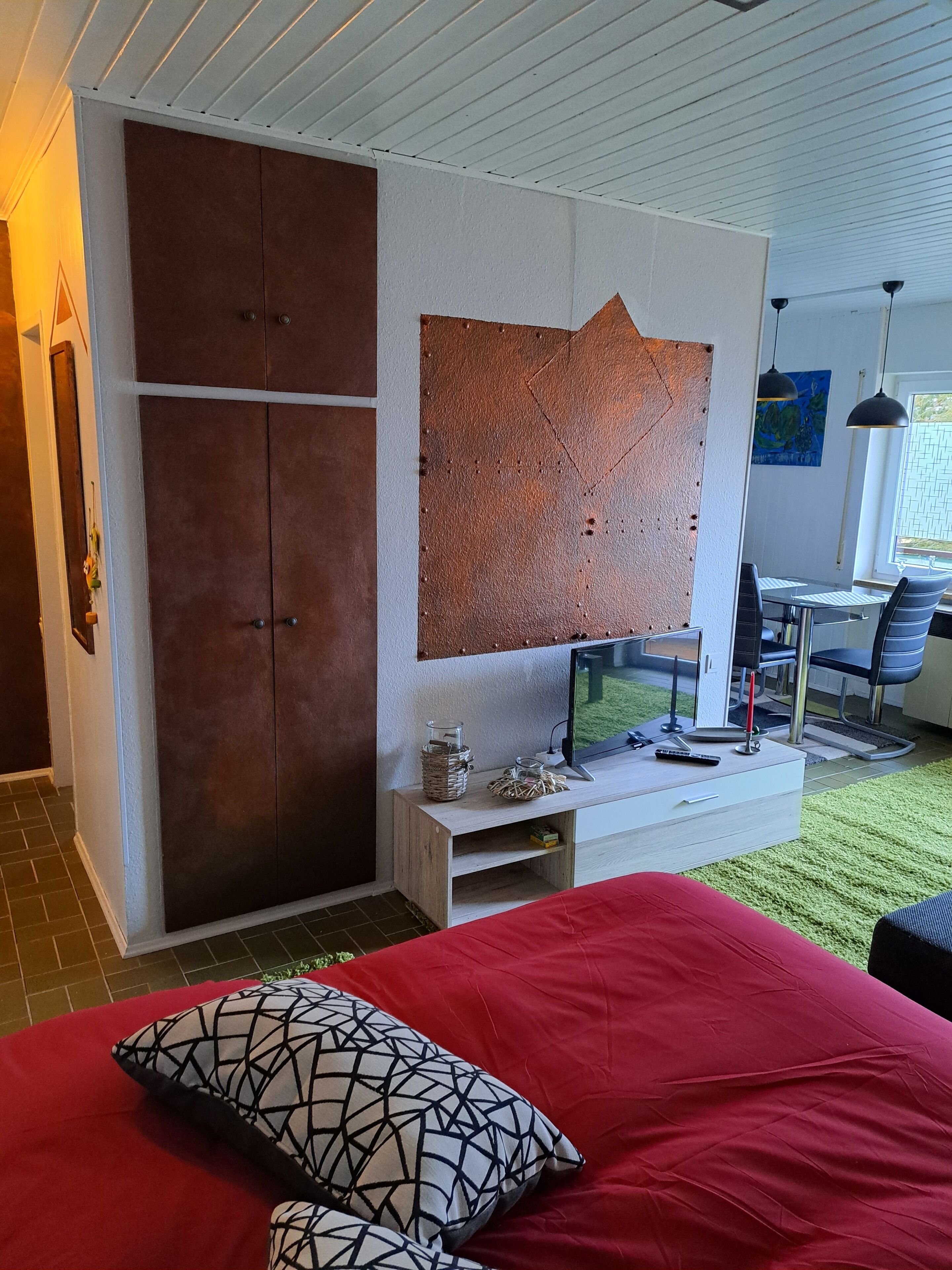 Ein Schlafzimmer mit Bett, Fernseher, Schreibtisch und Stuhl.