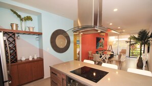 Una cocina moderna con estufa integrada, armarios de madera y un comedor con mesa y sillas.