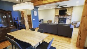A dining area with a wooden table and chairs, a blue rug, and a kitchen in the background. - LAKE Escape Retreat - Onsite Beach Dock Waterfront Boat Ramp (Amherstburg)