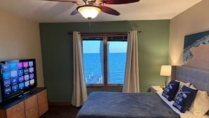 A bedroom with a bed, a television, a ceiling fan, and a window with curtains. - LAKE Escape Retreat - Onsite Beach Dock Waterfront Boat Ramp (Amherstburg)
