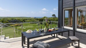 A deck with a table set for dining, overlooking a lush landscape. - Westaway House in Trelights near Port Isaac (Port Isaac)
