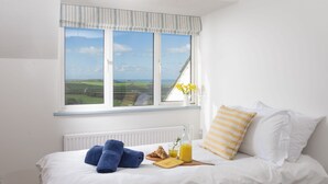 A neatly made bed with a view of the countryside through a large window. - Westaway House in Trelights near Port Isaac (Port Isaac)