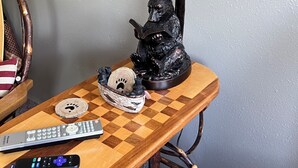 Una mesa con una lámpara, una figura de oso, un control remoto y un objeto decorativo.