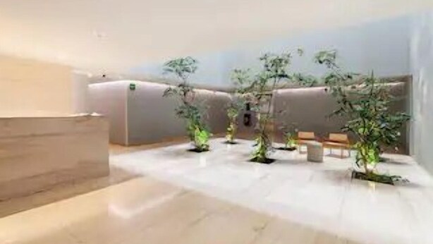 Een moderne hotellobby met een marmeren vloer, een zithoek en verschillende potplanten.