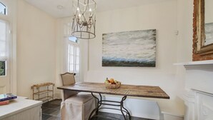Ein Essbereich mit einem Holztisch, einer Bank, einer Chandelüster und einem Gemälde an der Wand.
