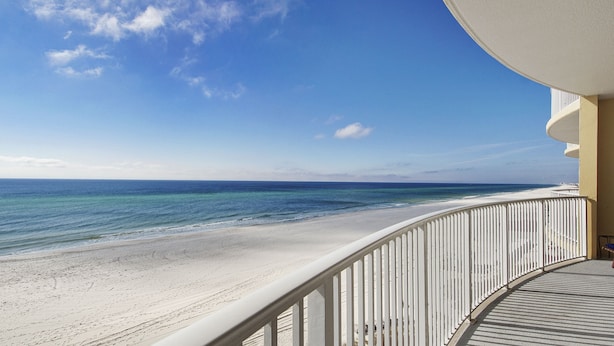 Un balcon avec vue sur une plage et l’océan.