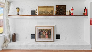 Ein Kamin aus weißen Ziegelsteinen mit Kaminvorsatz, der gerahmte Kunstwerke und dekorative Gegenstände zeigt.