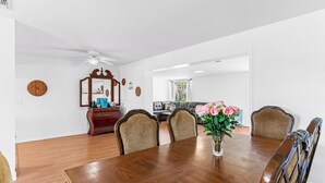 Ein Esszimmer mit Holztisch und -stühlen, einer Vase mit Blumen und einem Spiegel an der Wand.