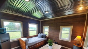 A compact room with a bed, a small table, a plant, and a lamp. - Hollering Pines Retreat-Great for Military, Fugitive Beach, in Mark Twain Forest (Newburg)