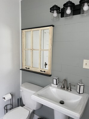 A bathroom with a white toilet, a white sink, and a wooden-framed mirror above the sink.