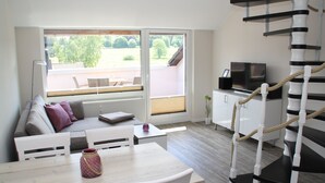 En moderne stue med sofa, spisebord og en spiraltrappe.